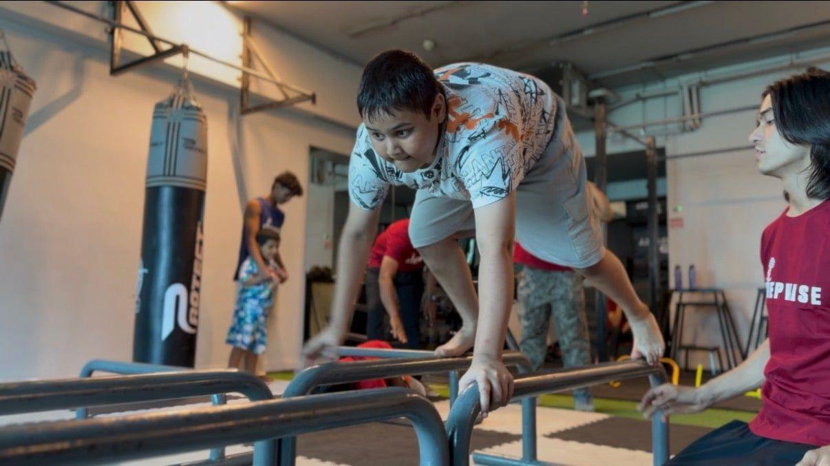 A child crossing the parallel bars with a coach steadying them