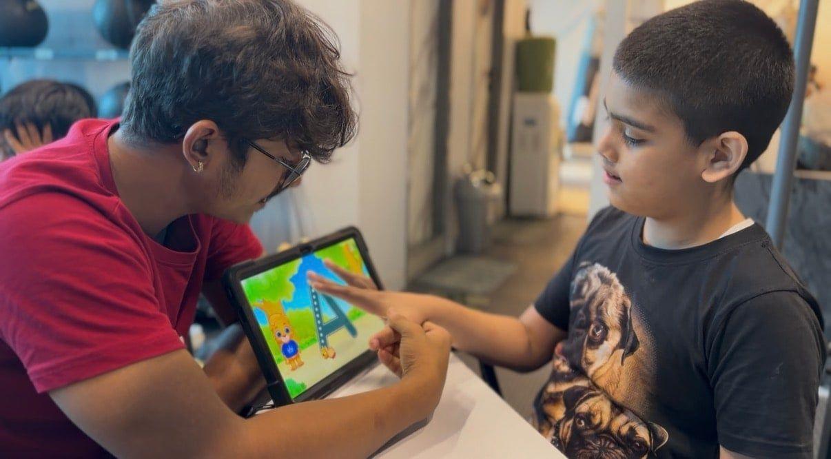 A coach and a child working together on a tablet activity