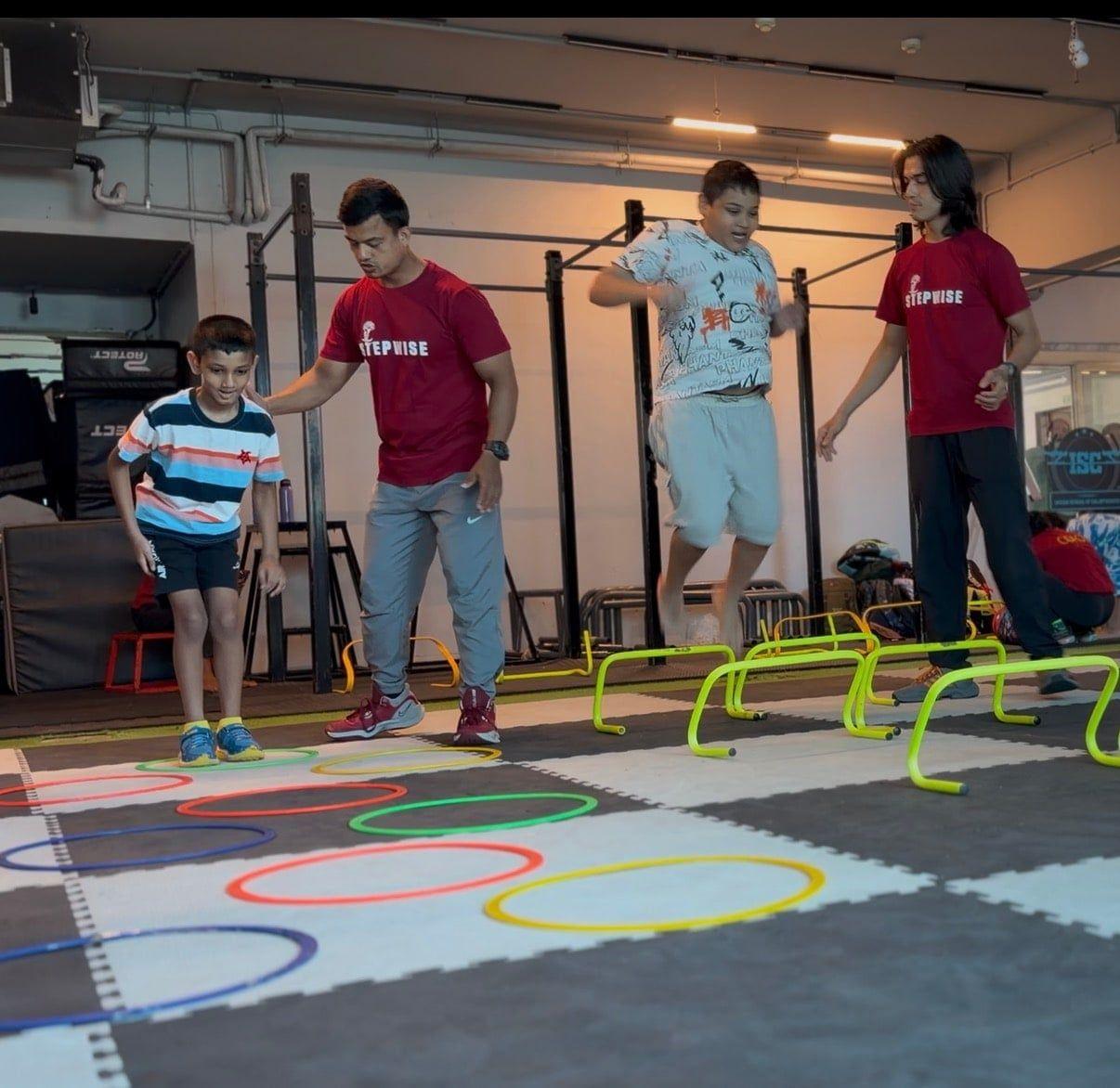 Children working through an agility ladder course with their coaches
