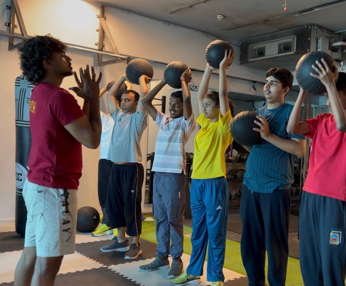 Children lifting medicine balls overhead together during a group fitness session