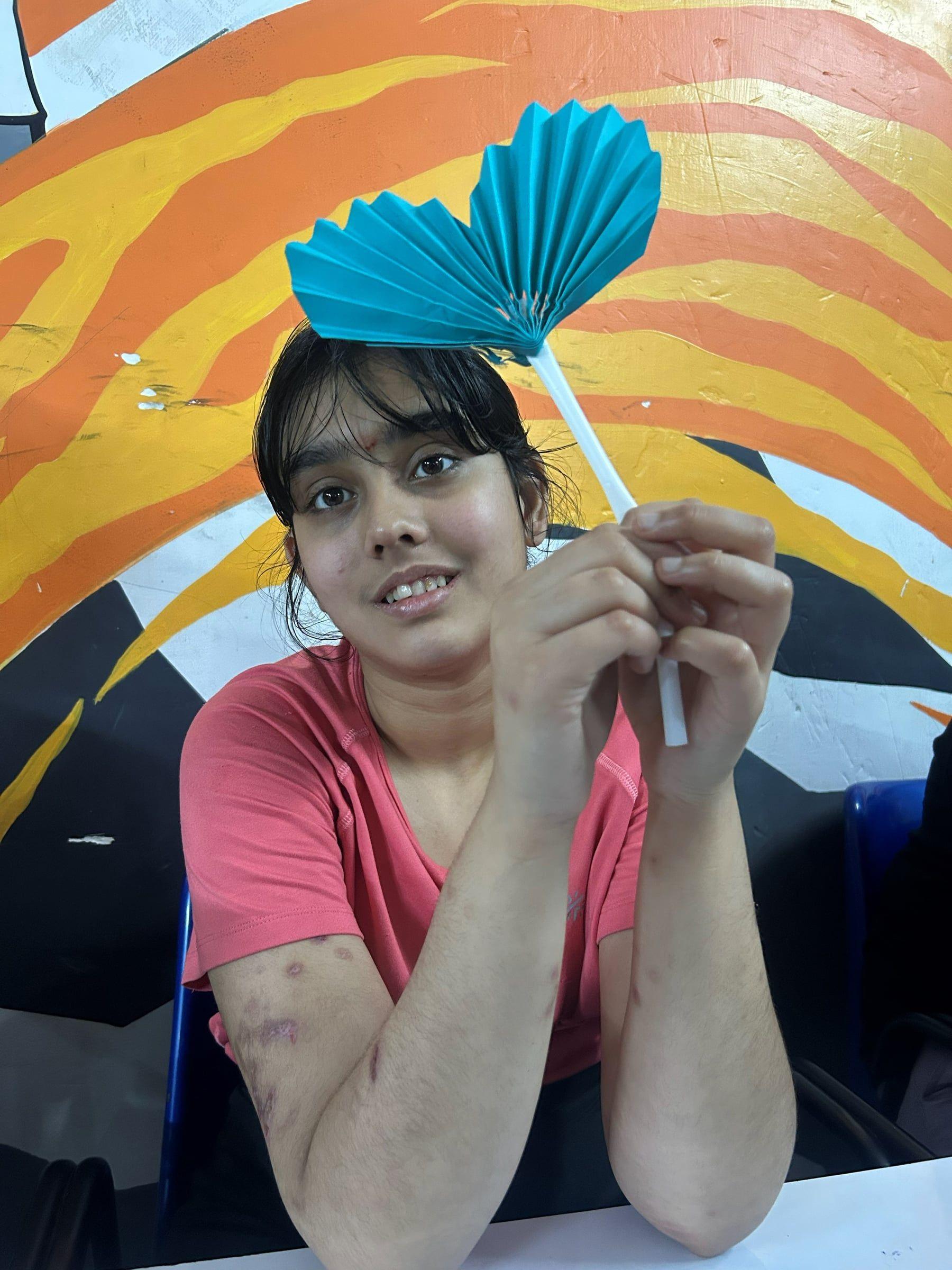 A student smiling with the paper craft she made
