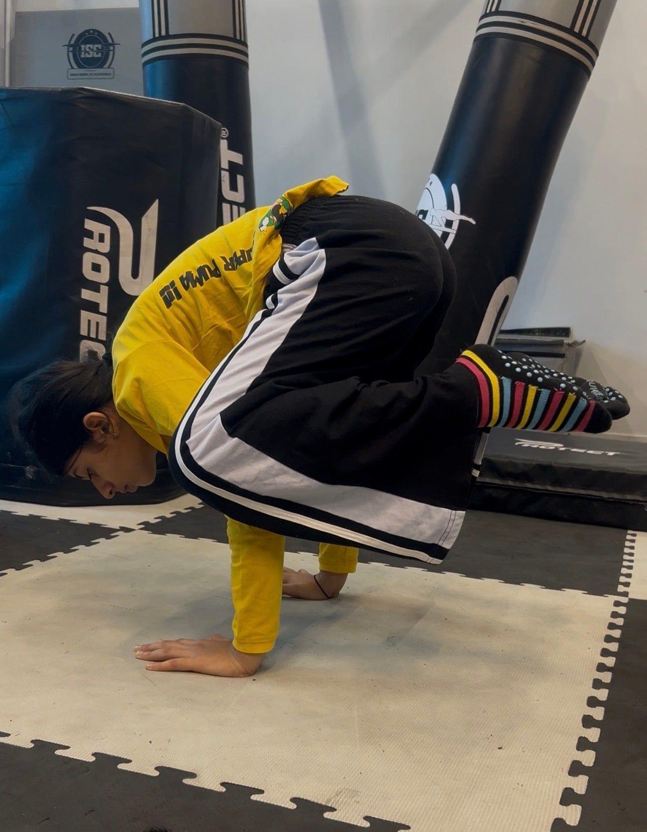 A child holding a handstand on the gym mat